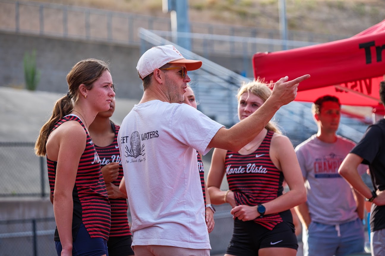 Coach Wales-Dinan, pointing, talks with Monte Vista girls in team singlets.